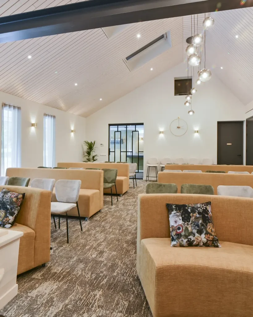 Lichte aula van rouwcentrum 't Waerdsche Hof met banken en stoelen